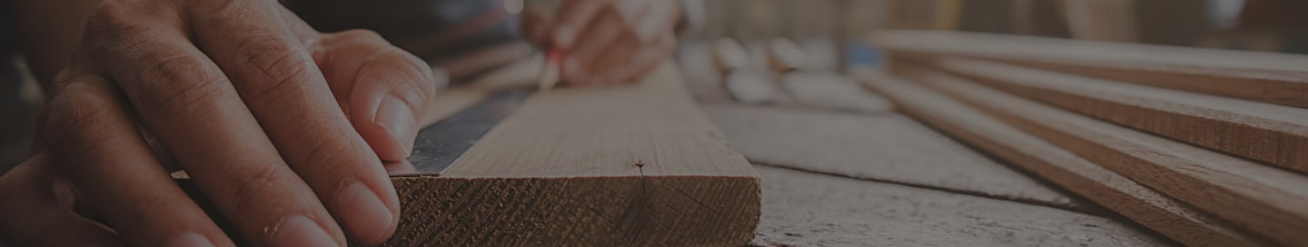 A carpenter measuring a piece of hardwood on-site A carpenter measuring a piece of hardwood on-site.
