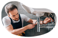 A plumber attaches a water line underneath a sink.